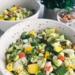 Two white bowls filled with a vibrant Squash Salsa featuring diced zucchini, yellow squash, bell peppers, onions, and fresh herbs. A small bowl of dried chili flakes and a green plant add charm to the background.