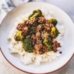 Vegan Beef And Broccoli Over Rice on White plate on table.