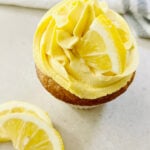 One vegan lemon cupcake with yellow frosting on tabletop.